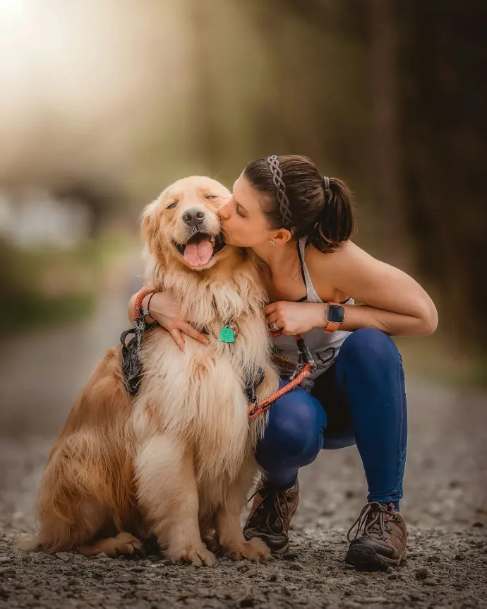 a woman kissing her dog on the cheek